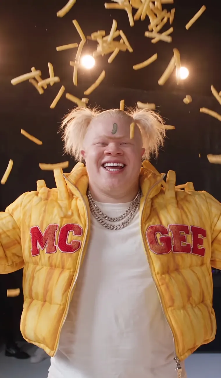 Fries McGee laughing with his arms out while fries rain down on him